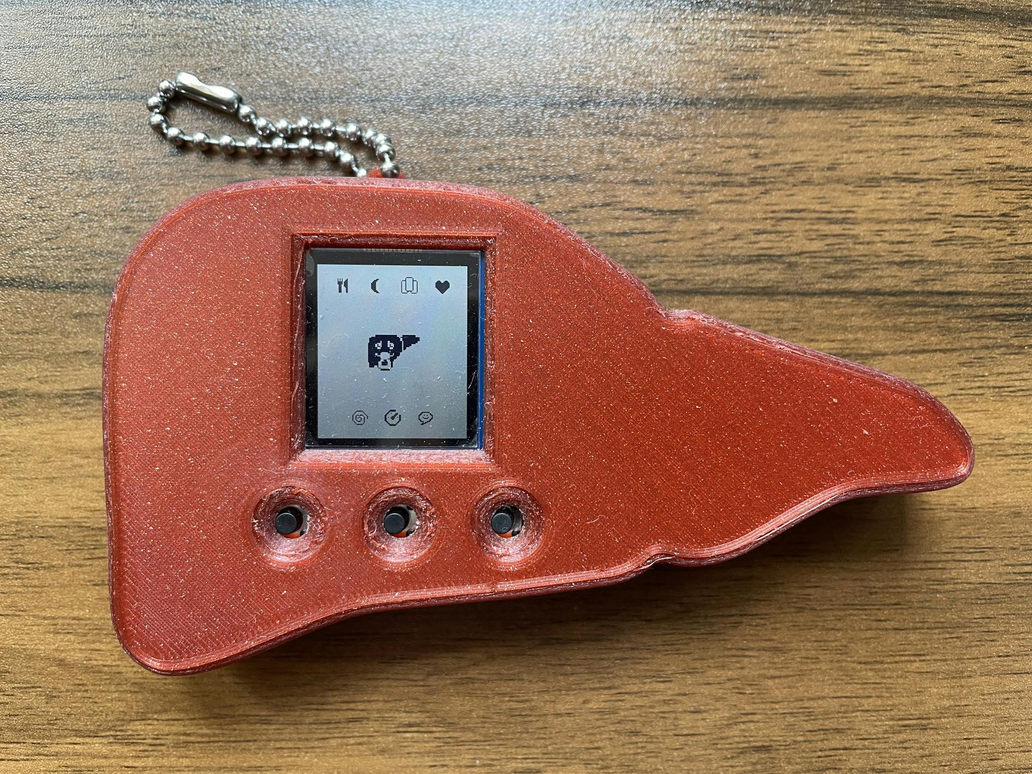 A tamagotchi-like toy, in the shape of a liver with a digital image of a liver on screen in pixel art.